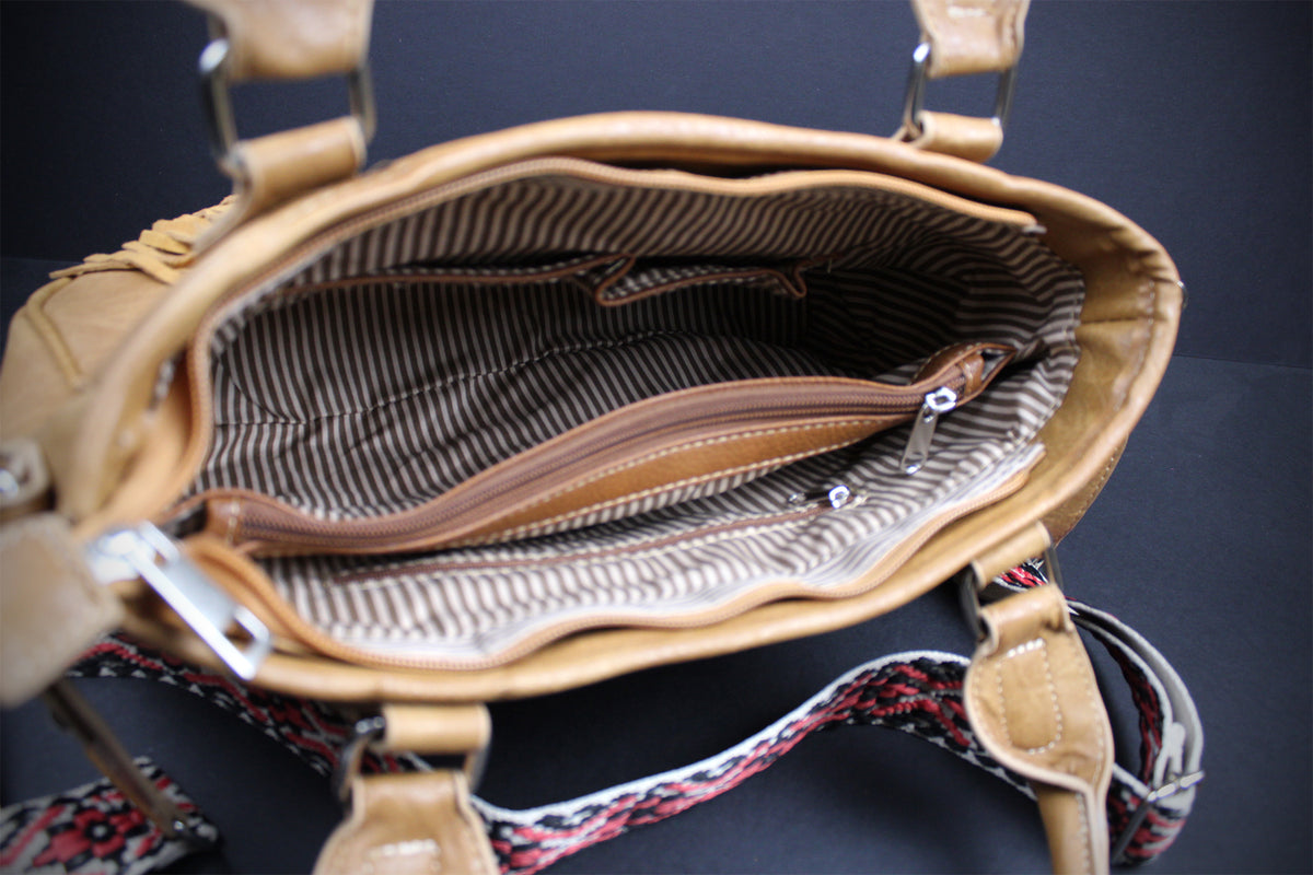 Close-up of the interior of a tan leather handbag with a striped fabric lining and a zippered pocket, shown against a dark background.
