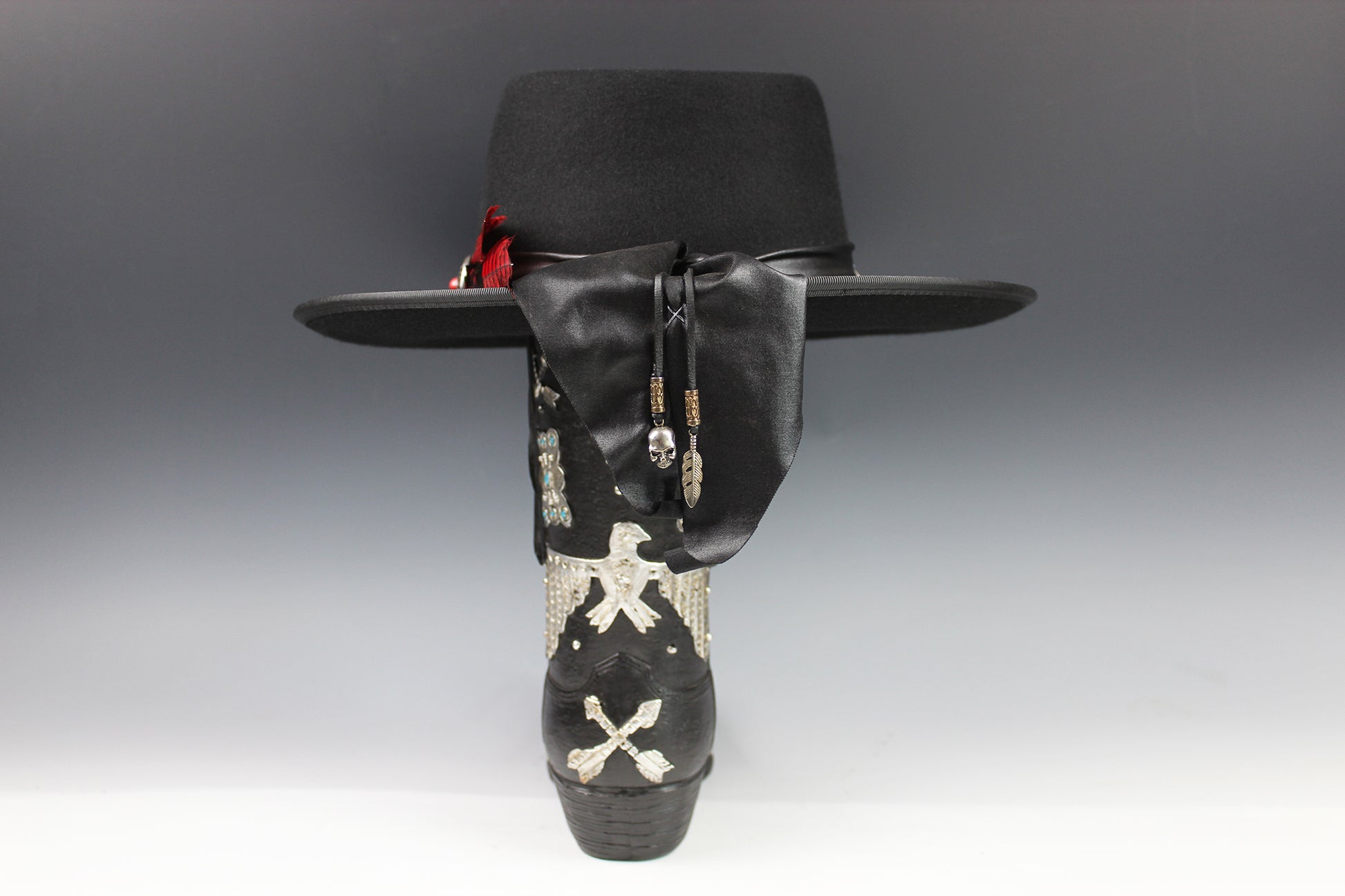 Black cowboy hat with decorative band featuring skulls and crossbones on a gray background