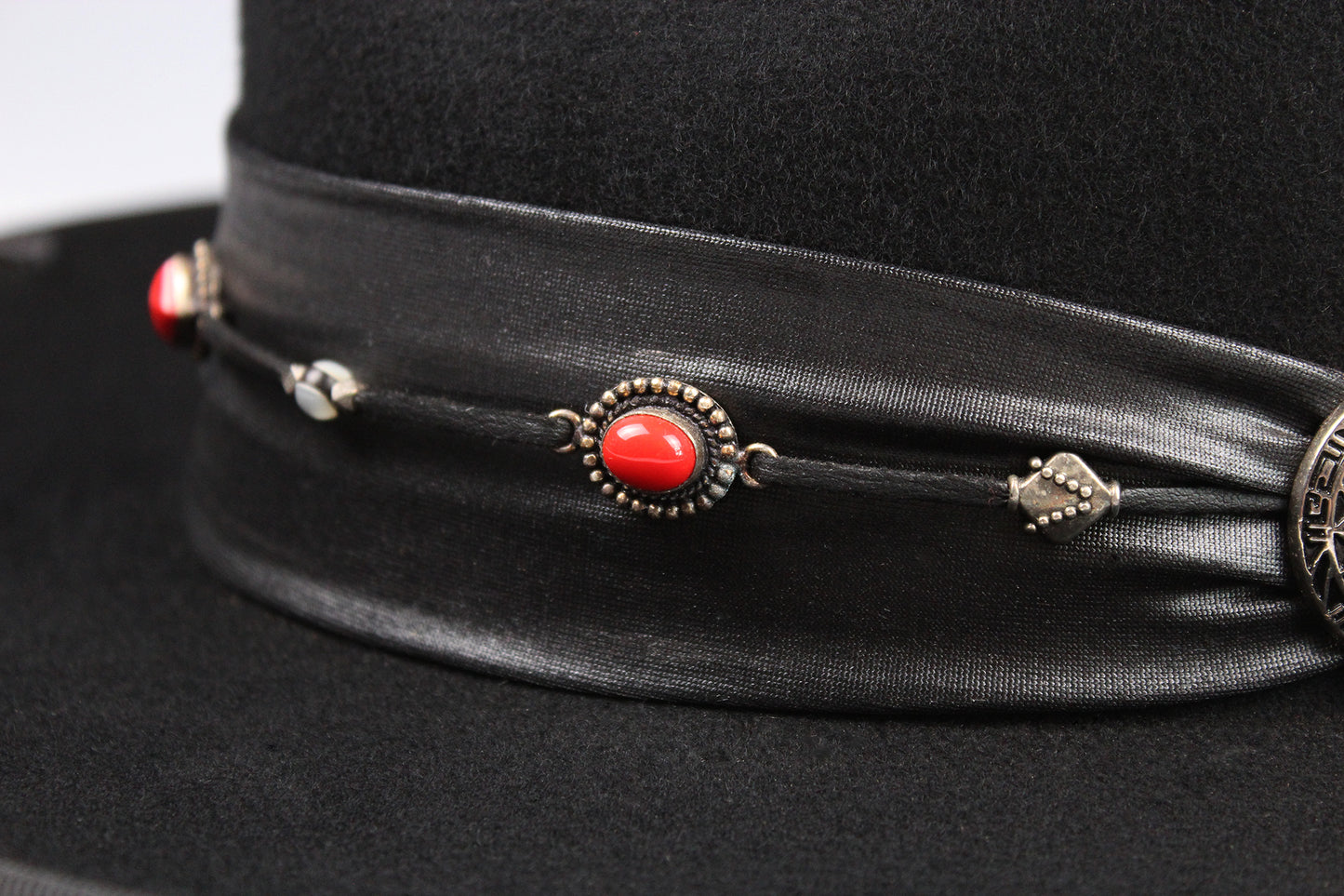 Black hat with decorative band featuring red stone and silver elements