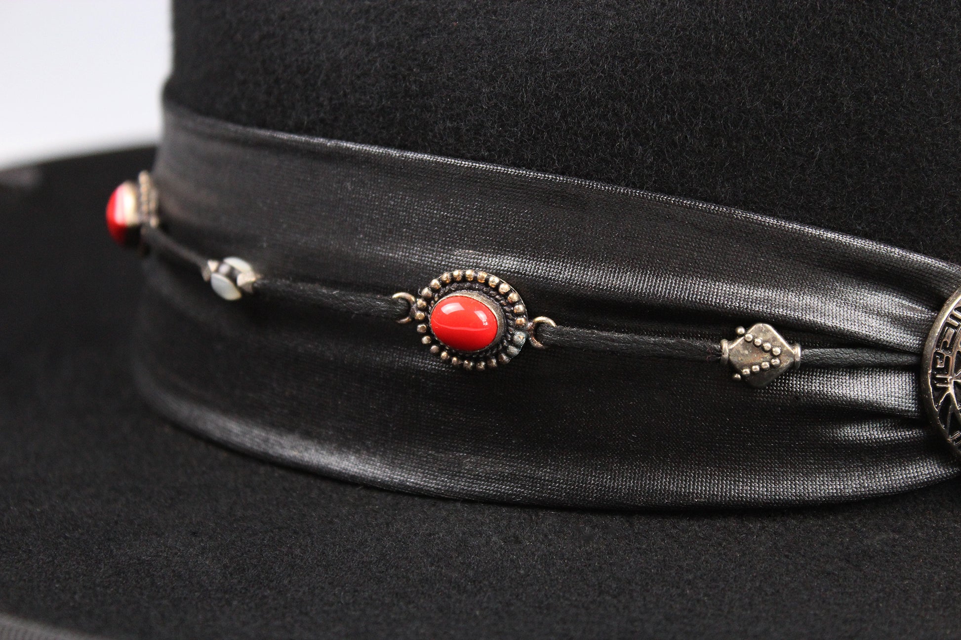 Black hat with decorative band featuring red stone and silver elements