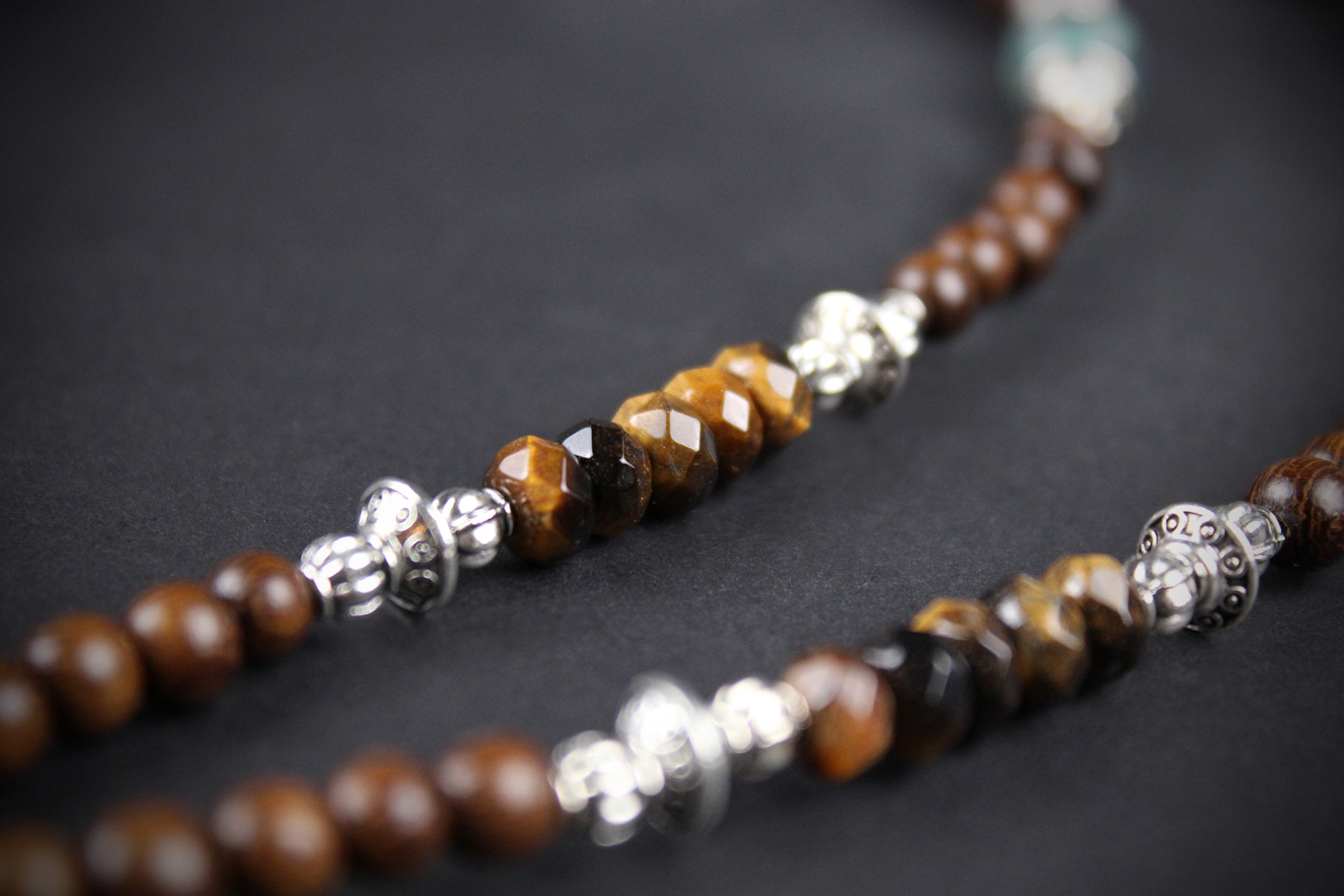 Necklace with brown beads and silver accents on a dark background