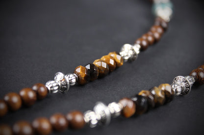 Necklace with brown beads and silver accents on a dark background