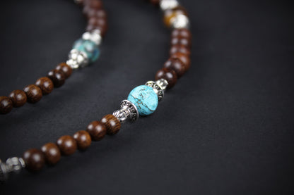 Beaded necklace with brown, turquoise, and silver beads on a dark background