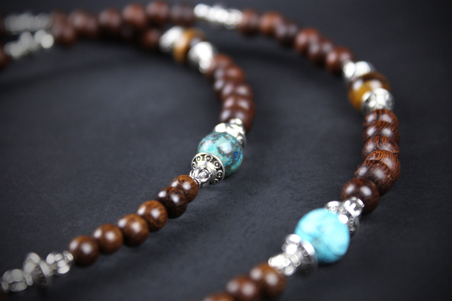 Beaded necklace with brown, turquoise, and silver beads on a dark background
