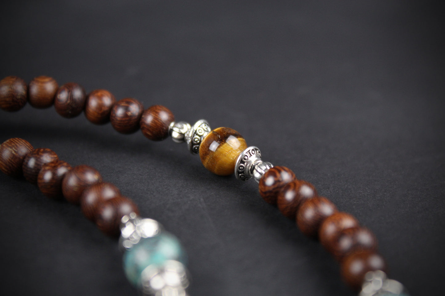 Close-up of a beaded bracelet with wooden beads and silver accents on a dark background