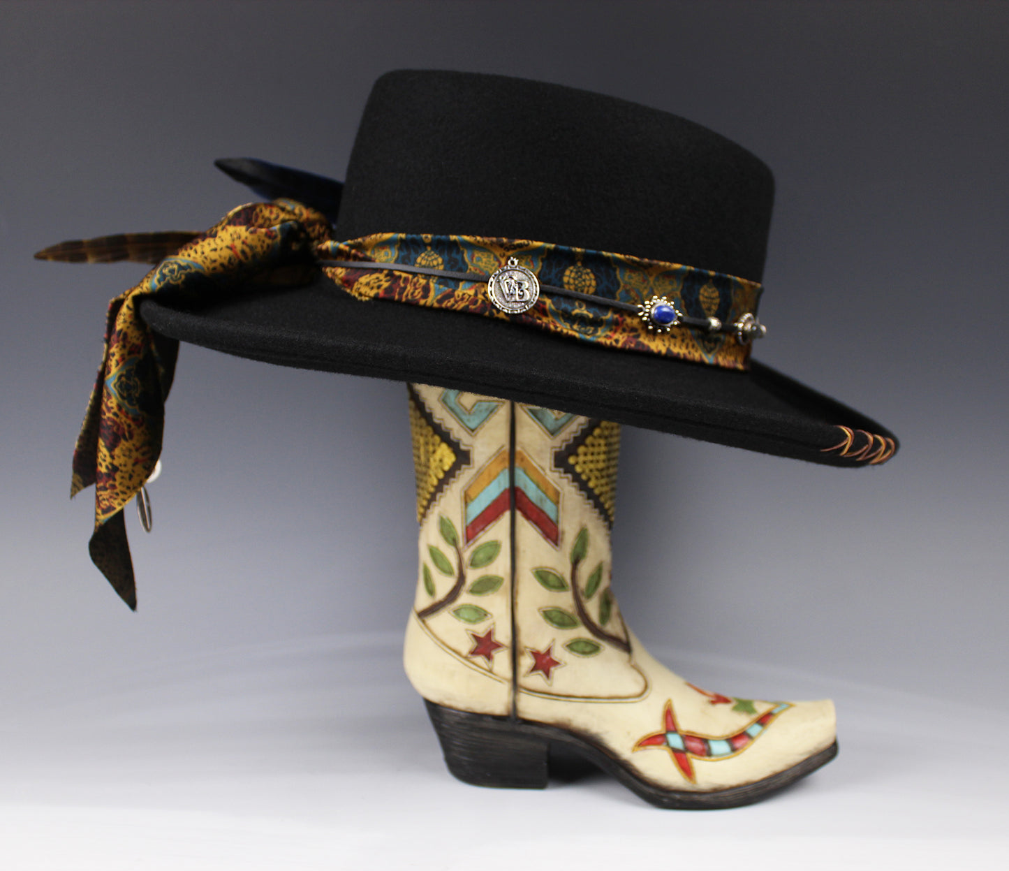 Decorative cowboy hat with a colorful band and a detailed boot on a gray background