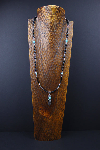 The Blue Wing Necklace, Detailed with hematite, howlite, black wood beads and silver beading, all of this leading to a very cool feather pendant.