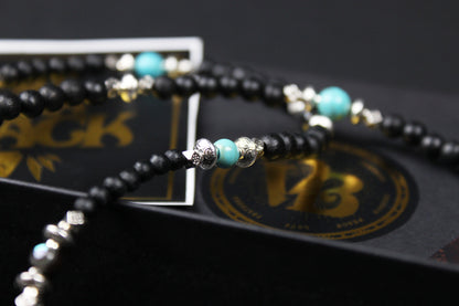The Blue Wing Necklace, Detailed with hematite, howlite, black wood beads and silver beading, all of this leading to a very cool feather pendant.