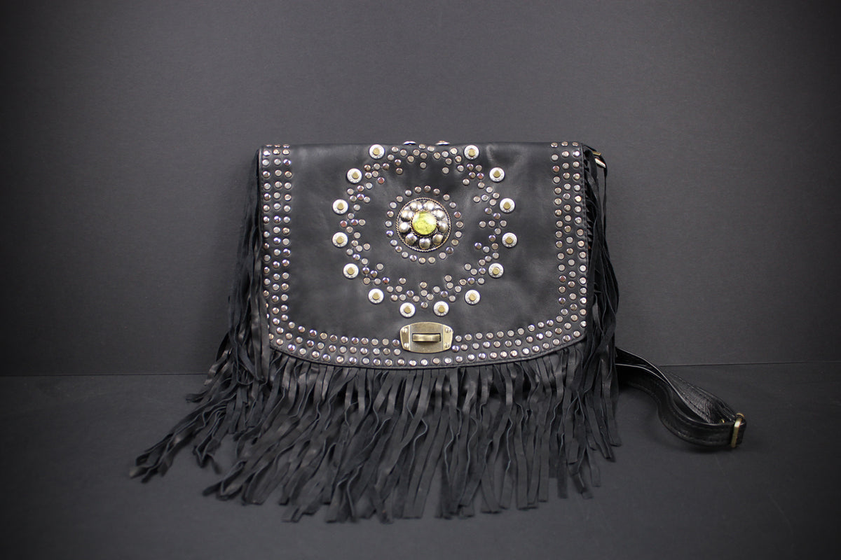 Black leather fringe clutch bag with silver studs, a central floral embellishment, and a gold-tone clasp, shown against a dark gray background.