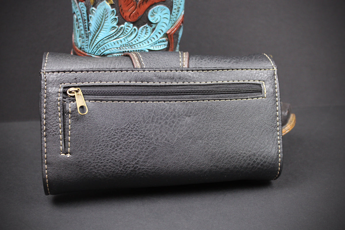 A black textured leather pouch with a horizontal zippered pocket and contrast stitching, shown against a dark background with a colorful patterned object partially visible behind it.