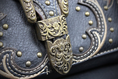 Close-up of a dark brown leather handbag with ornate embossed stitching, brass studs, and a decorative antique bronze buckle with floral scrollwork.