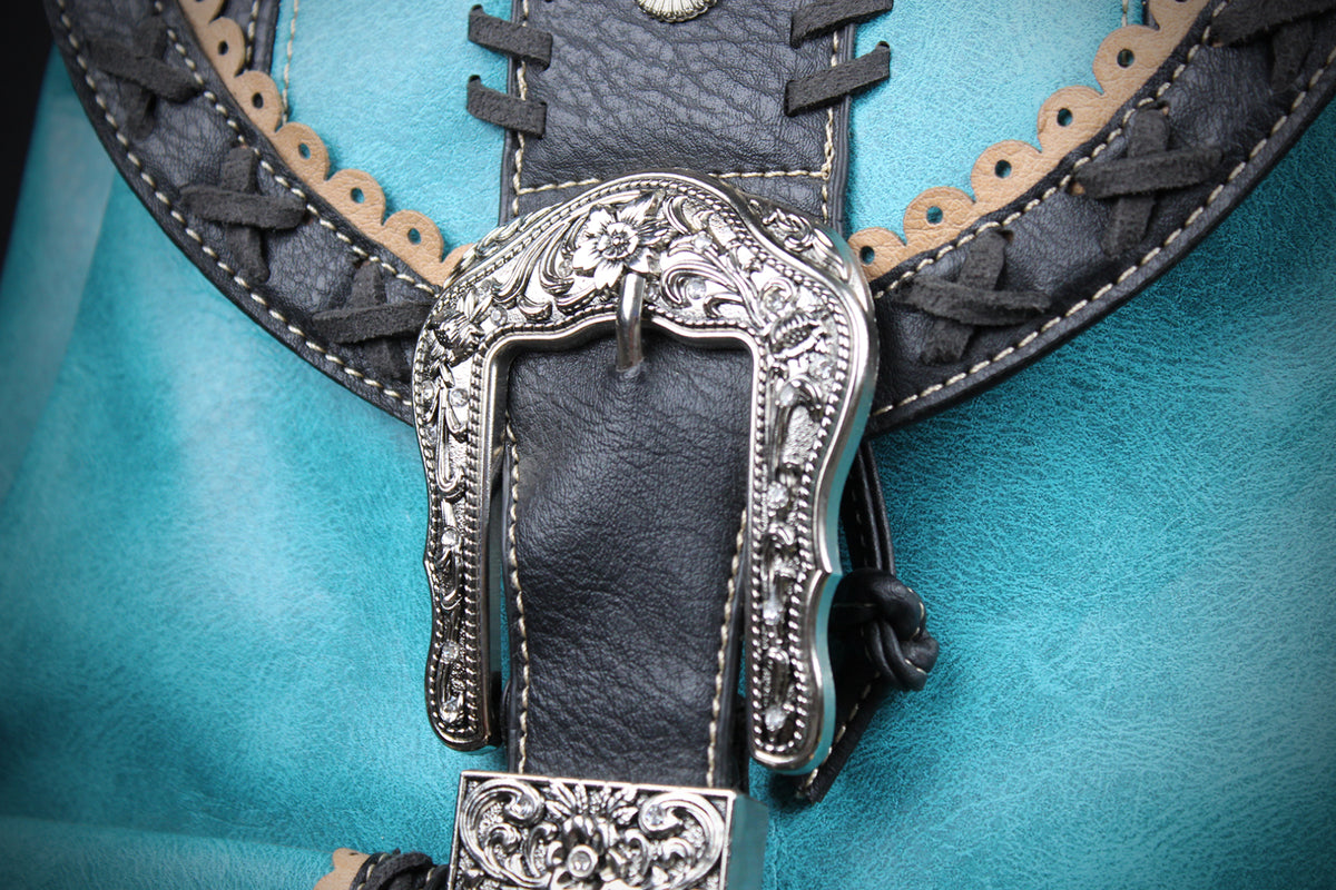 Close-up of a western-style leather belt with a large ornate silver buckle, black leather strap, tan braided trim, and a turquoise blue background.