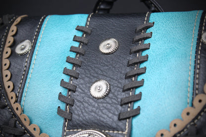 Close-up of a western-style leather bag featuring turquoise blue and black leather panels, decorative black laces, silver conchos, and scalloped trim.