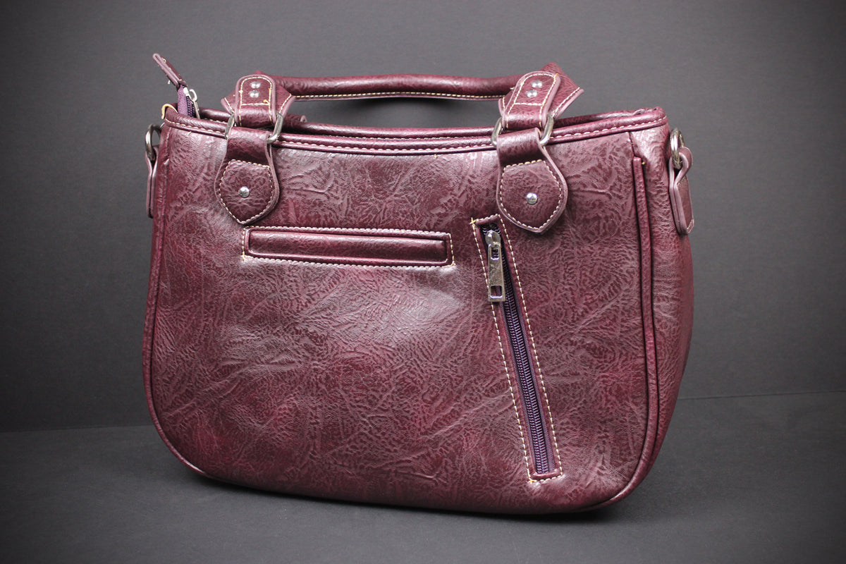 A distressed burgundy faux leather handbag with top handles, a front slip pocket, and a vertical zippered pocket on the side, shown against a dark gray background.