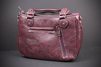 A distressed burgundy faux leather handbag with top handles, a front slip pocket, and a vertical zippered pocket on the side, shown against a dark gray background.