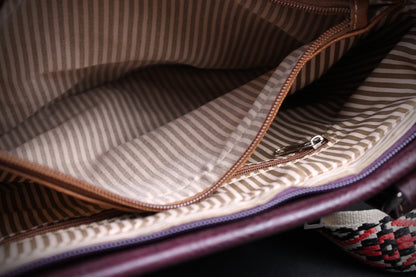 Close-up of the interior lining of a striped fabric bag, showing a brown zipper, beige and brown pinstriped material, and a dark purple outer edge.