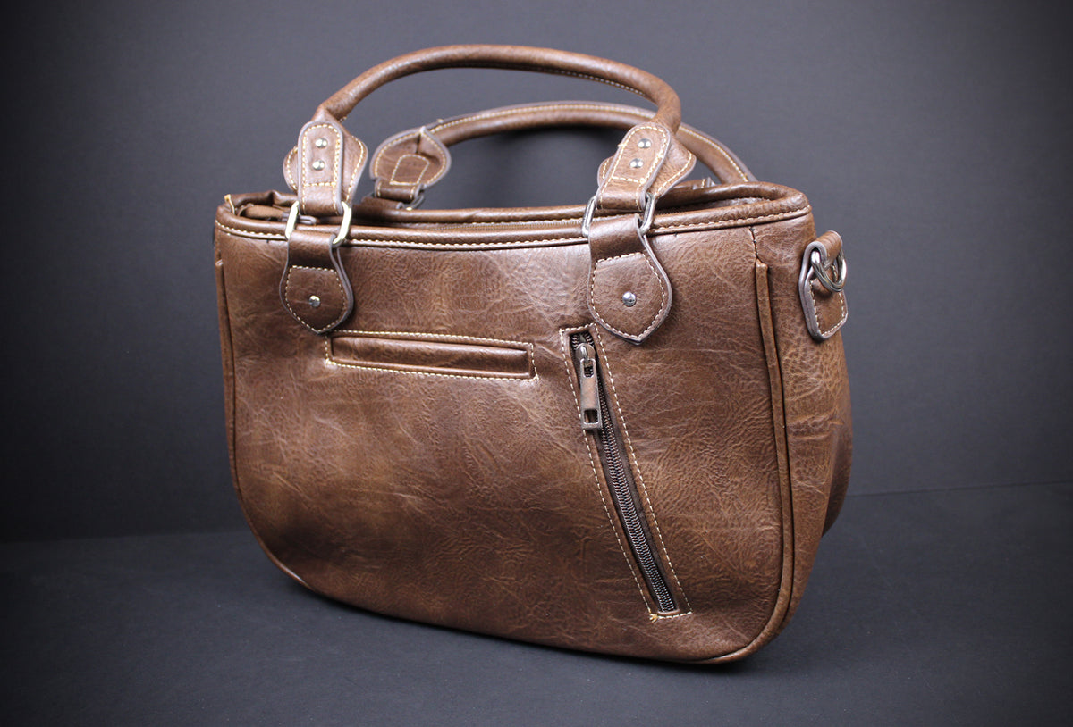 A brown textured leather handbag with dual top handles, a front zippered pocket, and a side slip pocket, photographed against a dark gray studio background.