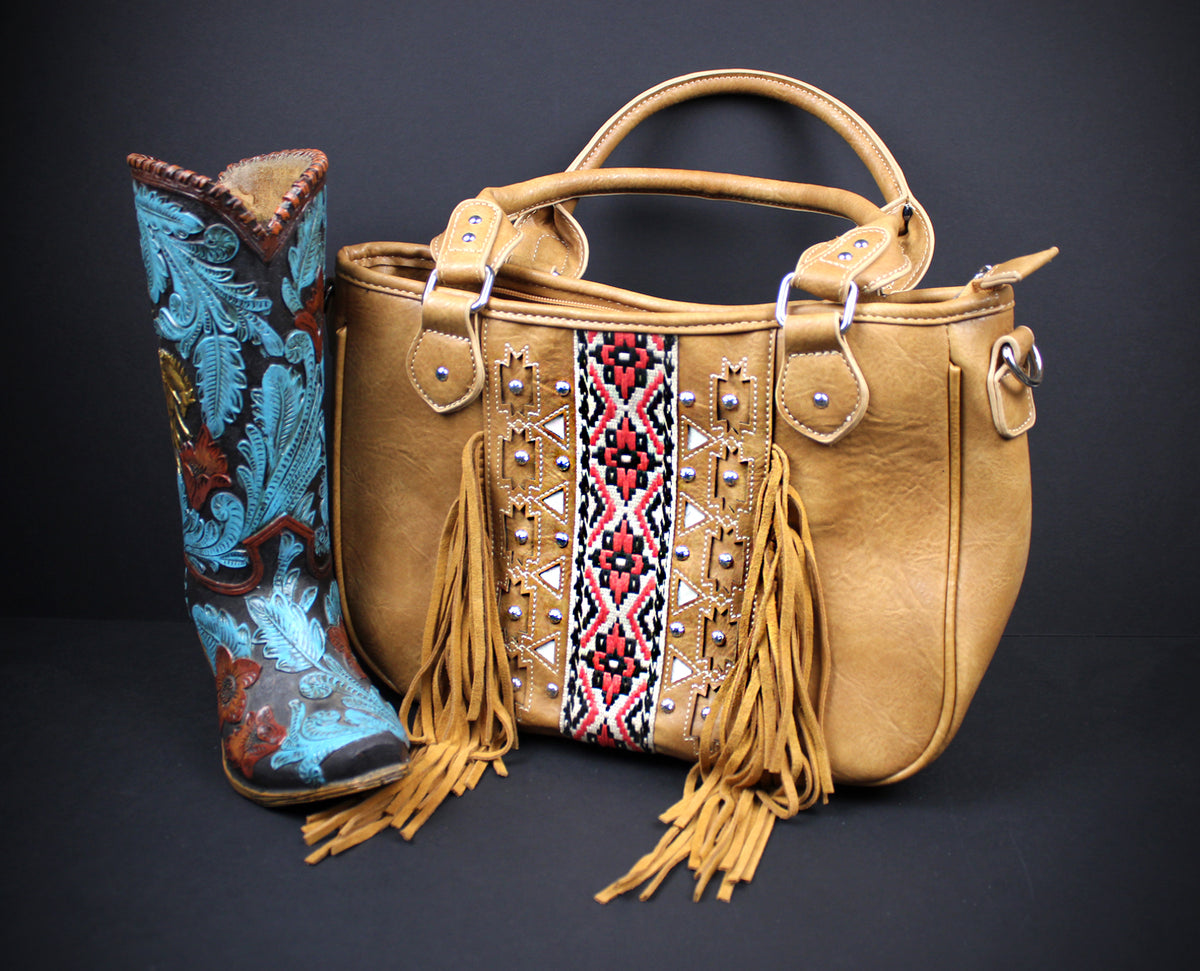 A tan leather handbag with fringe and a central geometric embroidered panel, displayed next to a tall western boot with turquoise, brown, and gold embossed detailing on a dark background.