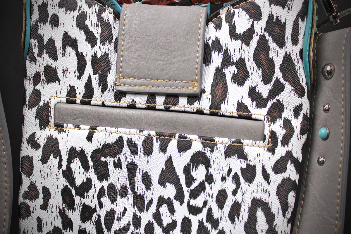 Close-up of a leopard print fabric bag with gray faux-leather trim, a front slip pocket, and a rectangular flap detail.