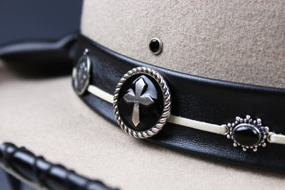 Close-up of a beige felt hat with a black leather band featuring silver-toned conchos and black oval stones.