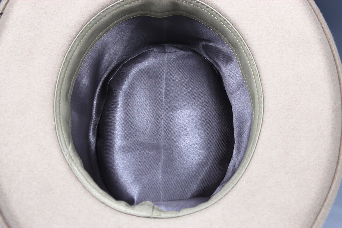 Close-up of the interior of a light beige hat, showing a smooth dark gray satin-like lining and a stitched rim.